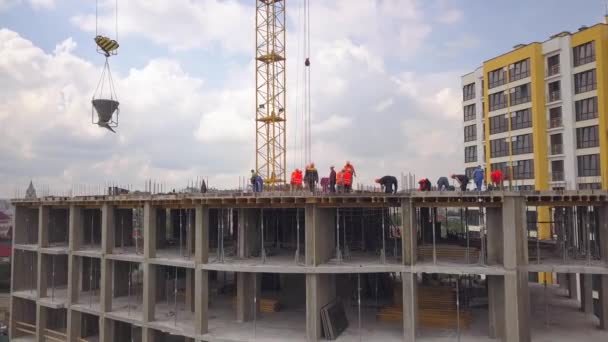 Будівельники працюють на будівельному майданчику нового бетонного житлового будинку
. - Кадри, відео