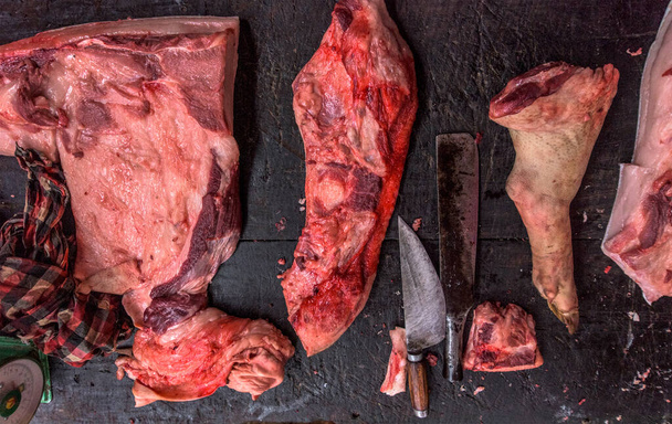 rauw vleesassortiment en mes op de donkere houten werktafel van de slager. Bovenaanzicht. - Foto, afbeelding