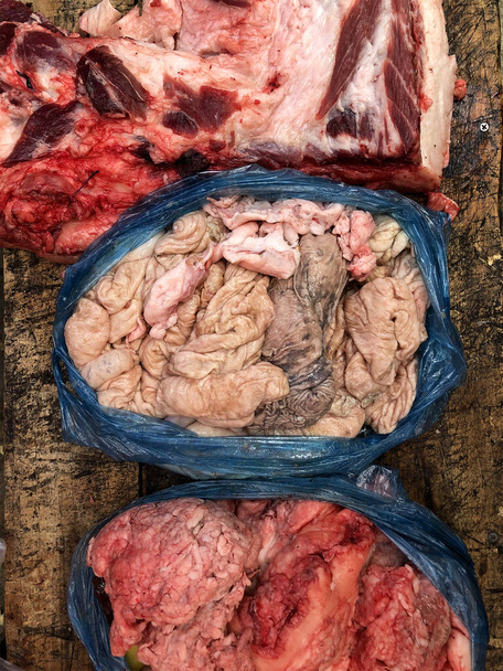 мясо в пластиковом пакете на тёмном деревянном рабочем столе мясника. Вид сверху
. - Фото, изображение