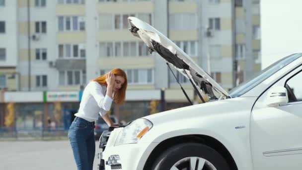Young stressed woman driver near broken car with popped hood having a prbreakdown problem with her vehicle waiting for assistance. - Materiał filmowy, wideo