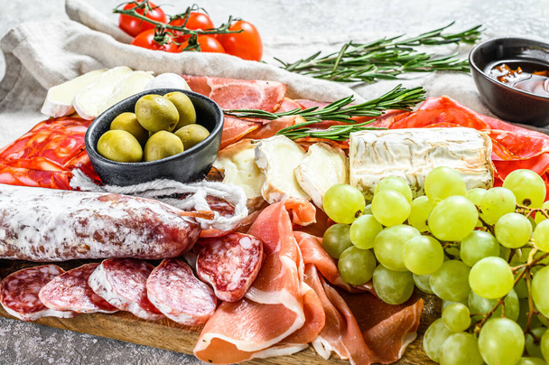Antipasto set platter. Cold smoked meat plate with sausage, sliced ham, prosciutto, bacon, olives. Appetizer variety. Gray background. Top view. - Photo, Image