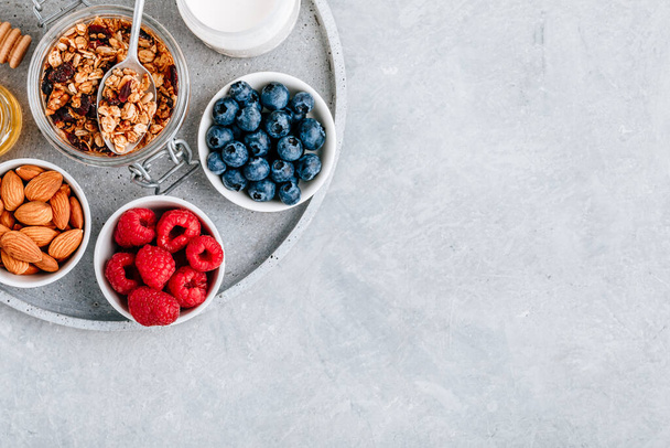 Granola cereals with fresh berries, almonds, milk and honey. Ingredients for healthy breakfast. - Photo, Image