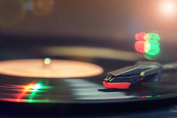 Retro record player com um disco de vinil preto girando refletindo luzes verdes e vermelhas - Foto, Imagem