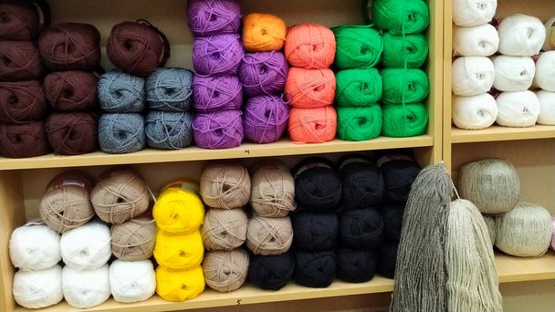 Skeins of yarn are on the shelves of the store. Balls of yarn for knitting. Colored threads are on the shelves. - Zdjęcie, obraz