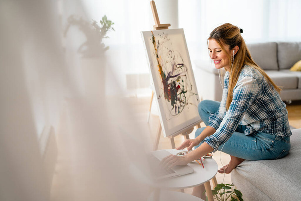 Art, creativity, hobby, job and creative occupation concept. Beautiful woman painting at home. - Photo, image