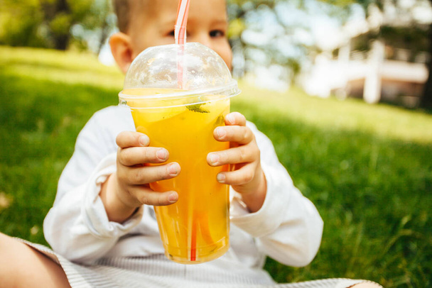 Chico gracioso bebiendo una limonada fresca a través de una pajita
 - Foto, Imagen