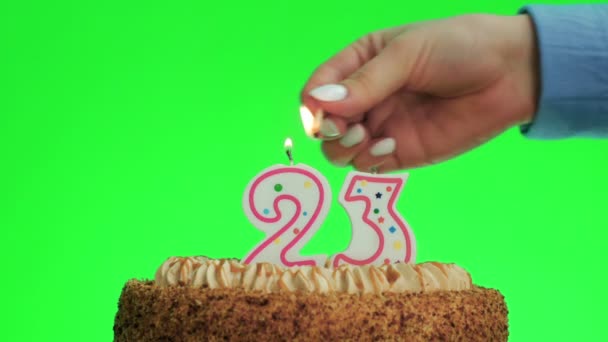Meggyújtani egy 23-as számú szülinapi gyertyát egy finom tortán, zöld képernyő 23 - Felvétel, videó