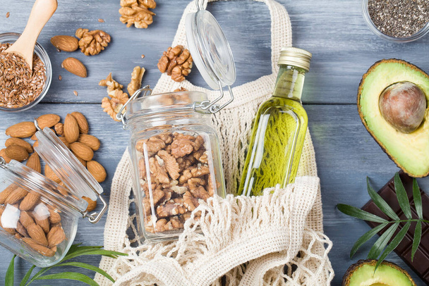 здоровые источники жиров льняные орехи масло авокадо Chia семян и горький шоколад на голубом фоне древесины.
, - Фото, изображение