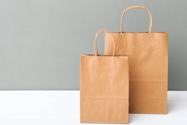 Brown craft paper bags. Empty cardboard paper package. Shopping Mock up bags on white table gray background with copy space. Shopping Food delivery service - Φωτογραφία, εικόνα