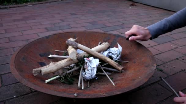 Une personne allume un feu de camp Avec du papier et un briquet dans un bol, fermer
 - Séquence, vidéo