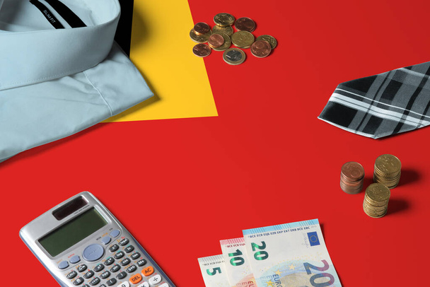 East Timor flag on minimal money concept table. Coins and financial objects on flag surface. National economy theme. - Fotografie, Obrázek