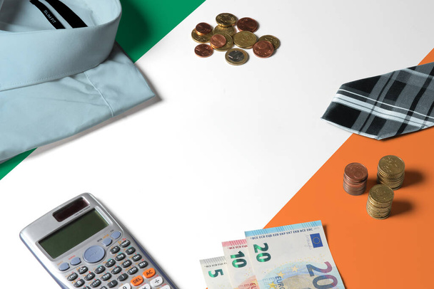 Ireland flag on minimal money concept table. Coins and financial objects on flag surface. National economy theme. - Fotografie, Obrázek