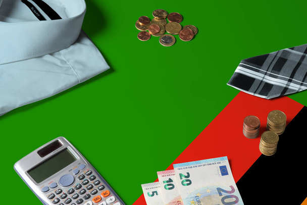 Zambijská vlajka na minimálním koncipovacím stole. Mince a finanční objekty na povrchu vlajky. Téma národního hospodářství. - Fotografie, Obrázek
