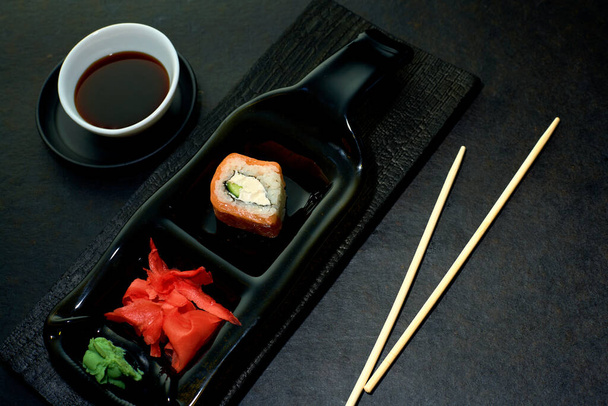 Alkuperäinen ajatus tarjoilla sushia rullaa ravintolassa. Sushi roll, inkivääri, wasabi tummalla pohjalla. Yläkuva
. - Valokuva, kuva