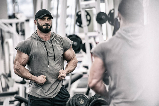 powerful strong young bearded man with beard showing muscle in sport fitness gym - Photo, image