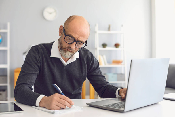 Online education. Mature man with a gray beard in teaches learning a university lecture online video call at home. - Foto, Imagem