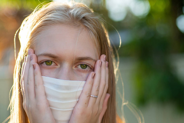 Ένα κορίτσι που φοράει χειροποίητη μάσκα προσώπου από βαμβάκι για να αποτρέψει την εξάπλωση των ιών. Coronavirus και COVID-19 Έννοια - Φωτογραφία, εικόνα