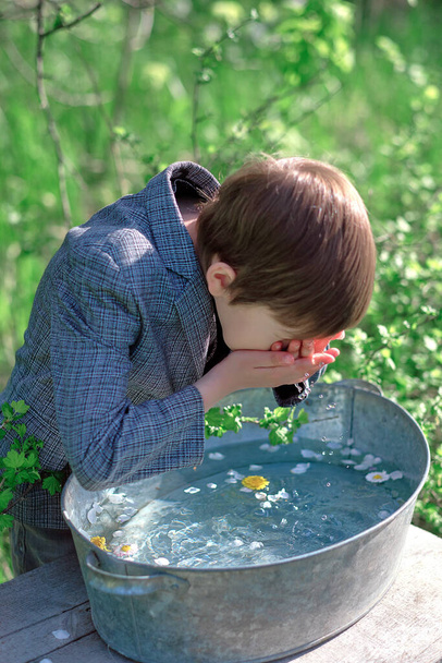 boy washes his face in water with flowers - Valokuva, kuva