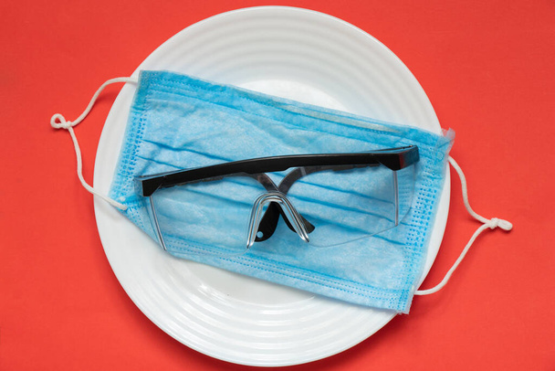 máscara médica y gafas sobre un fondo aislado en un plato
 - Foto, Imagen
