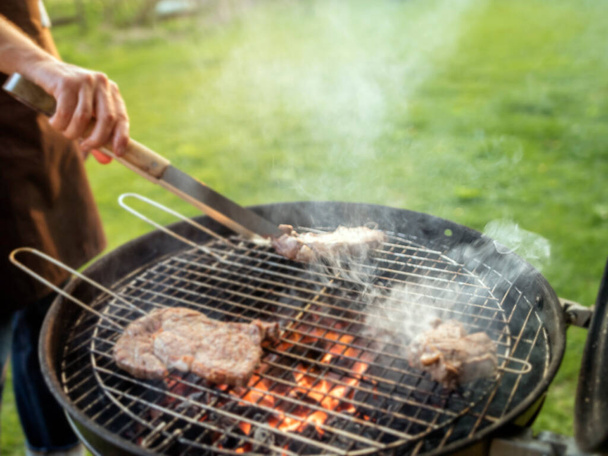 Defocused scene of a man grilling meat outdoor. - Foto, Imagen