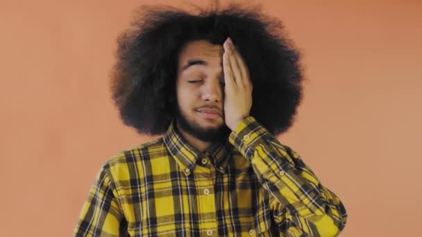 Csalódott afro-amerikai férfi arcpakolás narancssárga háttér mellett. Az érzelmek fogalma - Felvétel, videó