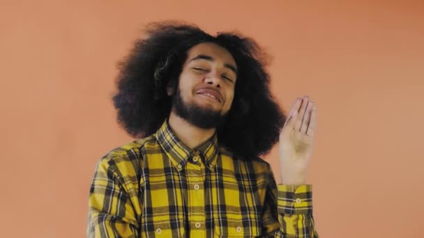 Joven afroamericano mostrando silencio o gesto bla bla sobre fondo naranja. Concepto de emociones
 - Metraje, vídeo