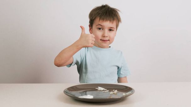 Um menino com uma máscara preta tenta adivinhar uma variedade de alimentos e dá polegares para cima
 - Foto, Imagem