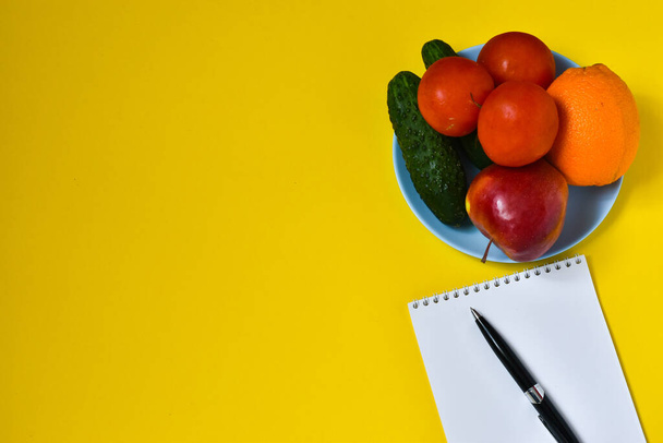 Fruits and vegetables, notebook for notes on a delt background. Tomatoes, cucumbers, apple, orange. The concept of a healthy diet, diet. Place for milking text. - Fotoğraf, Görsel