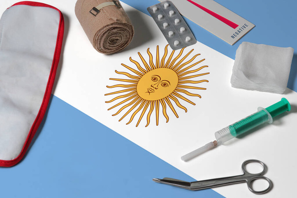 Argentina flag with first aid medical kit on wooden table background. National healthcare system concept, medical theme. - 写真・画像