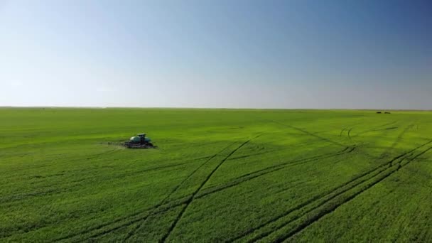 Luchtfoto van landbouwtrekkers die ploegen en sproeien op het veld - Video