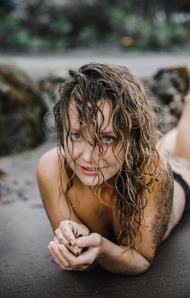 sexy blonde girl posing on black sand near the ocean on an exotic island Bali in Indonesia - 写真・画像