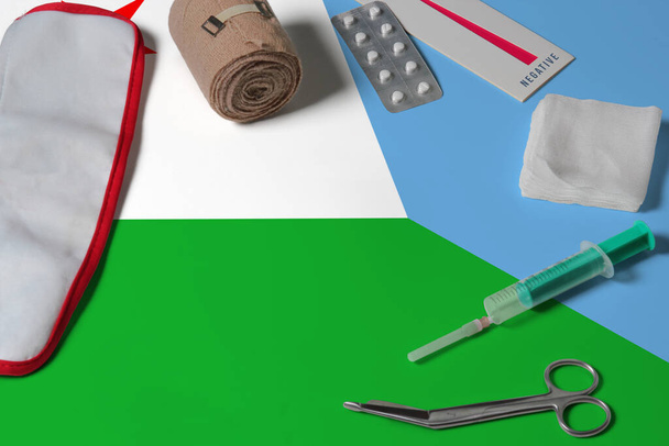 Djibouti flag with first aid medical kit on wooden table background. National healthcare system concept, medical theme. - Фото, зображення