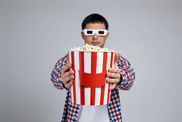 Человек в красно-синих 3D очках показывает ведро попкорна
 - Фото, изображение