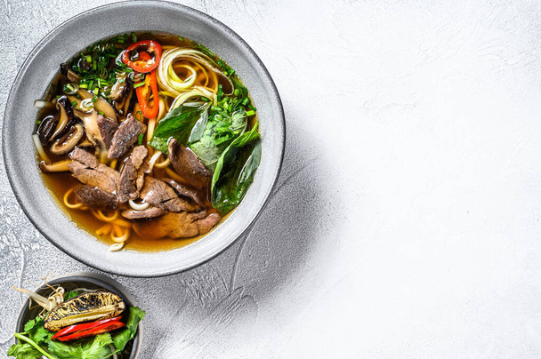 Pho Bo Vietnamese verse rijst noodle soep met rundvlees, kruiden en chili. Witte achtergrond. Bovenaanzicht. Kopieerruimte. - Foto, afbeelding
