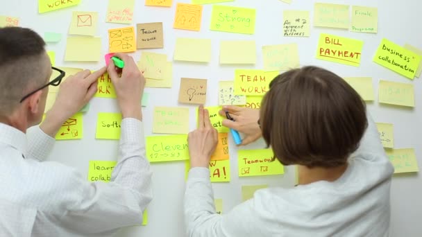 Zakenmensen schrijven een belangrijke notitie op, met behulp van de papieren stickers post. Brainstormen, teamwork.  - Video