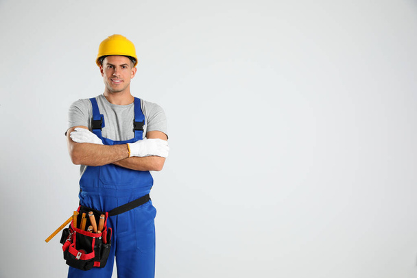 Carpenter with tool belt on light background. Space for text - Foto, Bild