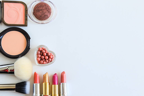 decorative cosmetics, powders, lipsticks, blush and makeup brushes lie on a white surface top view - 写真・画像