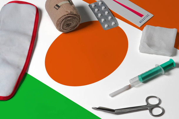 Niger flag with first aid medical kit on wooden table background. National healthcare system concept, medical theme. - Фото, зображення
