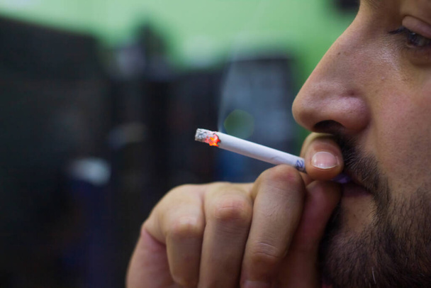επιχειρηματίας που καπνίζει τσιγάρο στο γραφείο του, νεαρός άνδρας που καπνίζει τσιγάρο - Φωτογραφία, εικόνα