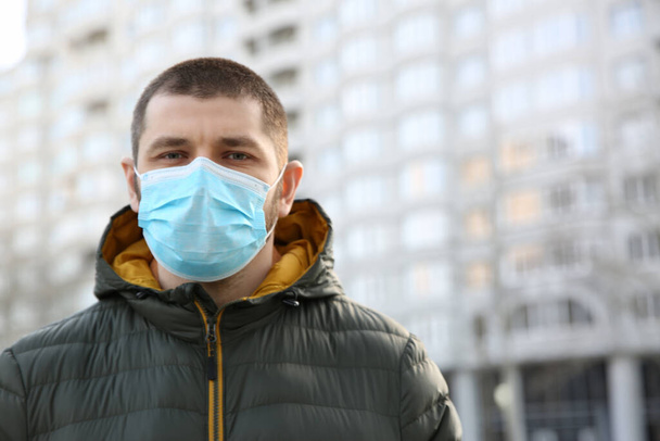 Man wearing disposable mask outdoors. Dangerous virus - Фото, изображение