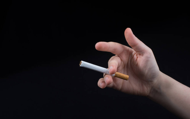 Hand is holding a cigarette on black background - Foto, Imagem
