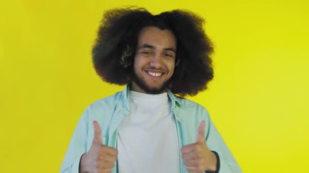 Африканський американець усміхається, коли дає пальці на жовтому фоні. Концепція емоцій - Кадри, відео