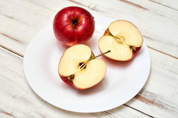Ripe red apples on a plate on a wooden background. - Fotoğraf, Görsel