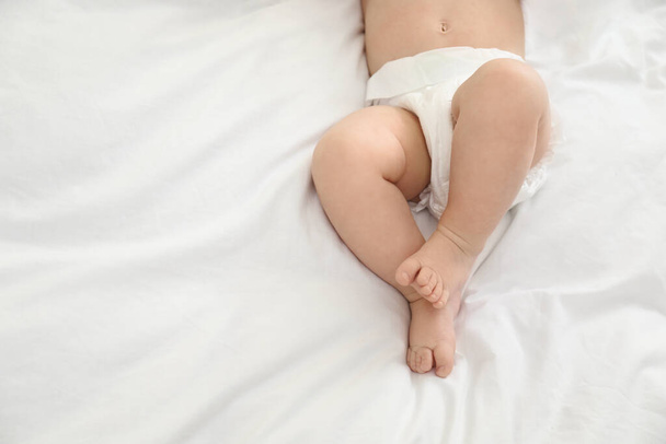 Cute little baby in diaper on bed, top view. Space for text - 写真・画像
