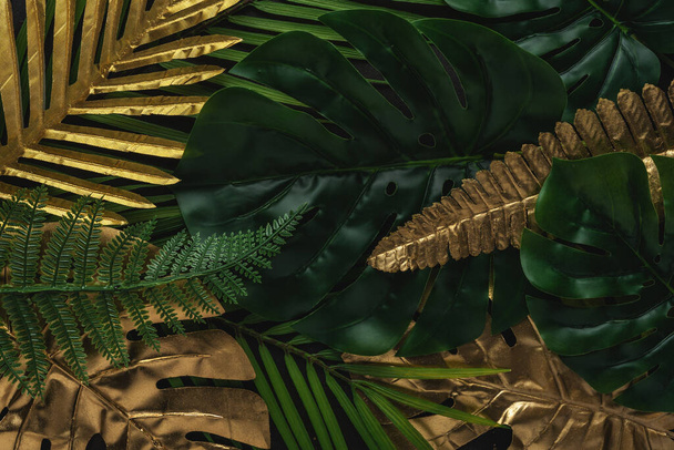 Creative layout with gold and green tropical palm leaves on black background. Minimal summer abstract pattern. - Zdjęcie, obraz