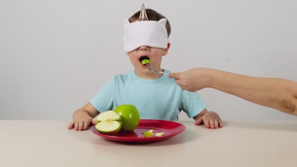 Kleine jongen in een masker probeert en raadt groene appel - Video