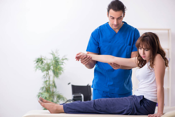Injured woman visiting young male doctor osteopath - Foto, imagen