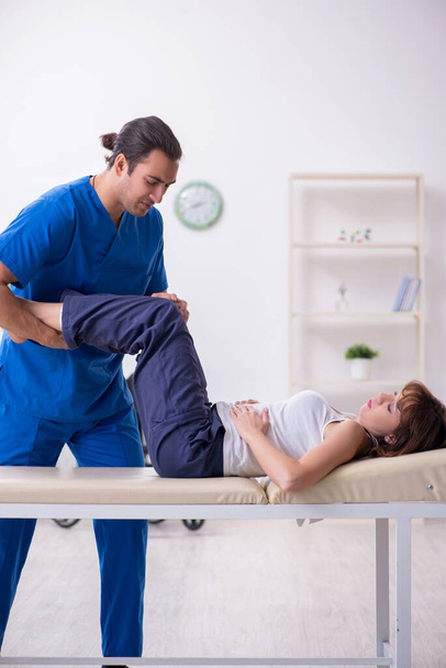 Verwondde vrouw bezoekt jonge mannelijke arts osteopaat - Foto, afbeelding