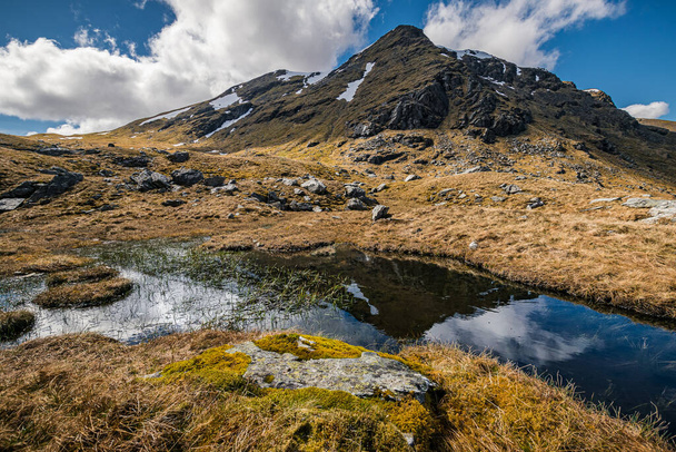 Гора віддзеркалюється в маленькому ставку на підйомі до Бейна Дорена в Шотландському нагір'ї. Раннє весняне шотландське нагір "я. - Фото, зображення