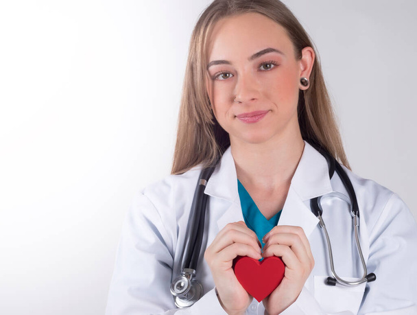 medical woman holding a red heart, on white background - Фото, изображение